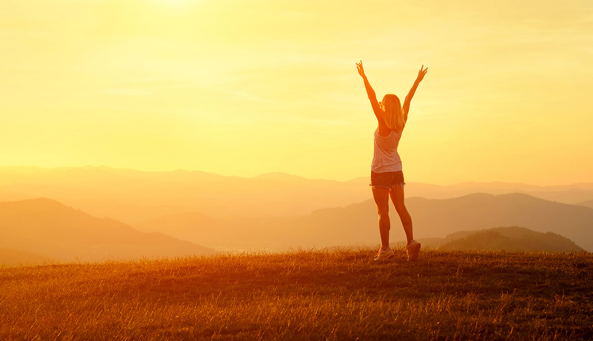 Besprechen von Krankheiten - Glückliche Frau vor Sonnenaufgang in Landschaft